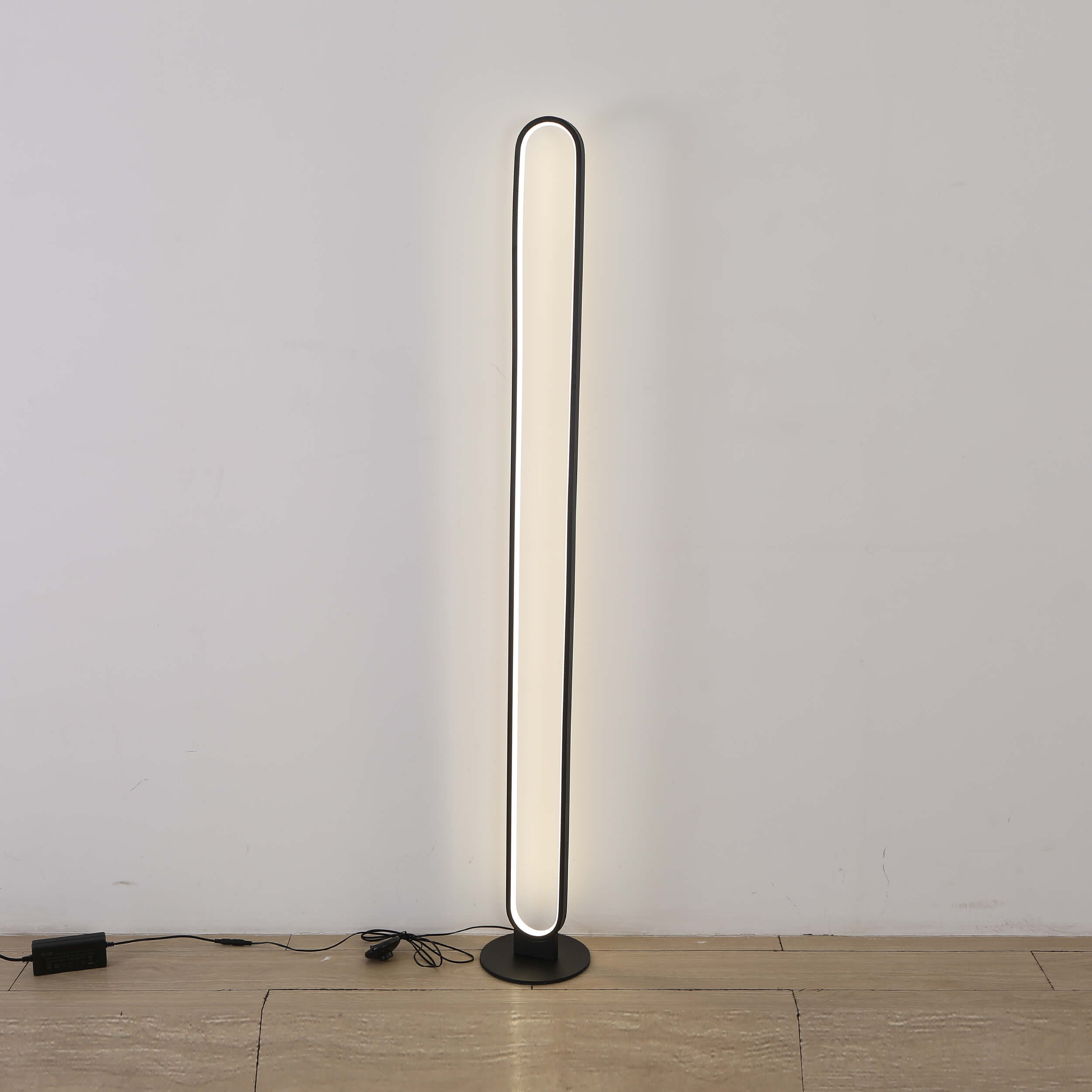 Sleek and modern black floor lamp with an elongated curved design, providing warm ambient lighting.